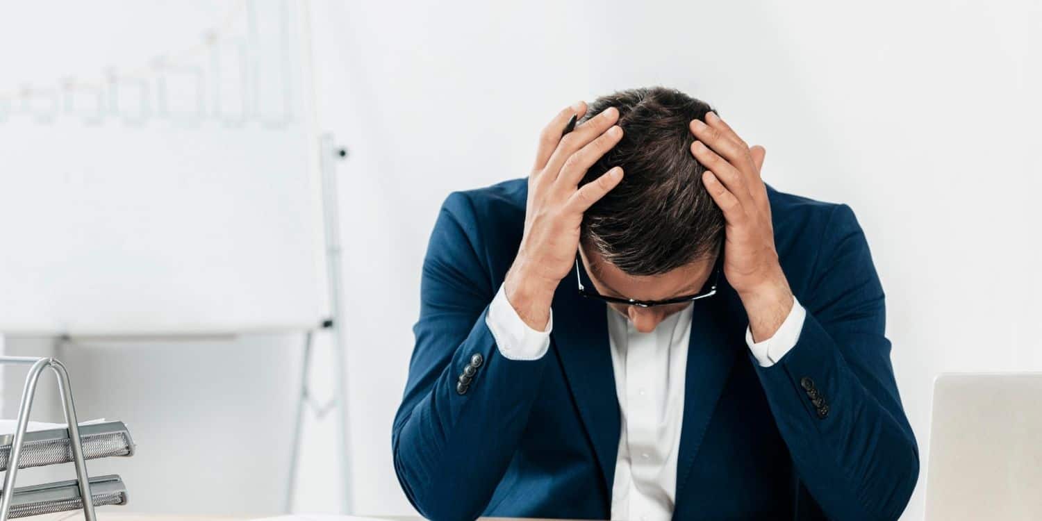 Caucasian man looking stressed at papers in a white and clean office area