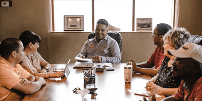 a team of people sitting at a conference table laughing and smiling during a meeting