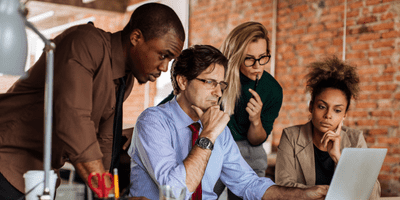 a team of two men and two women contemplating something on the screen of a laptop