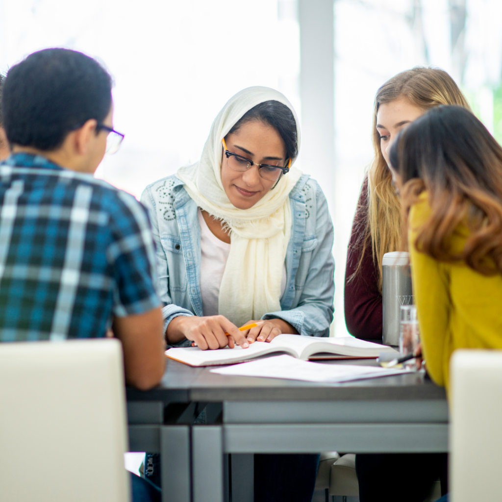 group of people in a meeting room around a table happy and in discussion