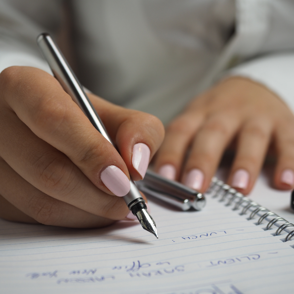 caucasian hands writing in a notebook