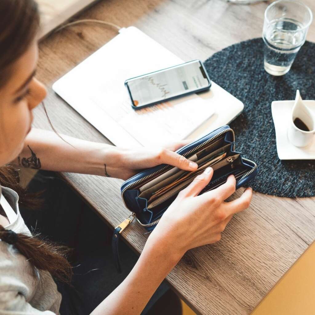 millennial getting money out of her wallet at a desk